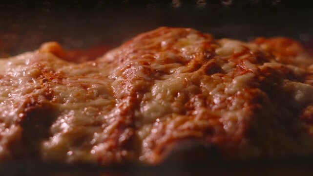 Slow Dolly Shot Across Bubbling Cheese Melting on Spicy Mexican Chicken Enchiladas Cooking in Hot Oven.