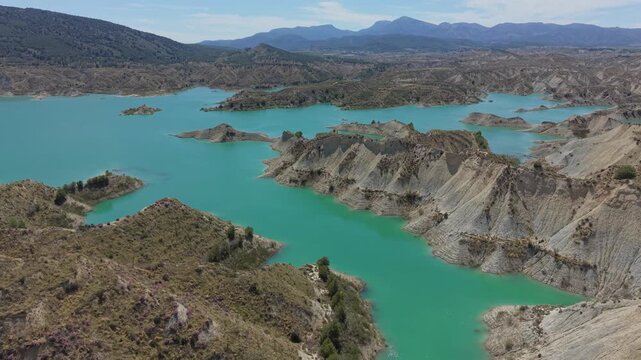 Drone aerial panorama of the turquoise waters and eroded badlands formations of Embalse de Negrat&iacute;n in Andalusia, Spain