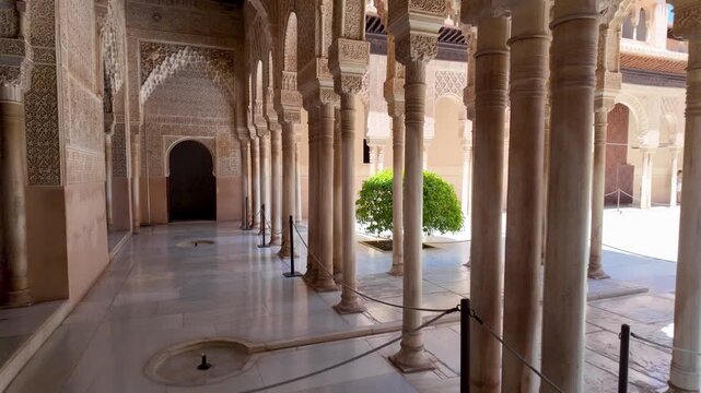 Slow motion movement through the colonnade of the Nasrid Palaces showcasing ornate Islamic architecture and the historic courtyard in Granada, Spain