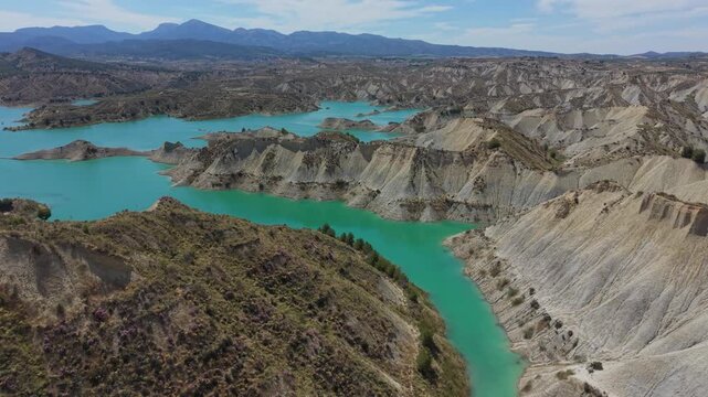 Drone pan across the turquoise waters and eroded badlands landscape of Embalse de Negrat&iacute;n in Andalusia, Spain
