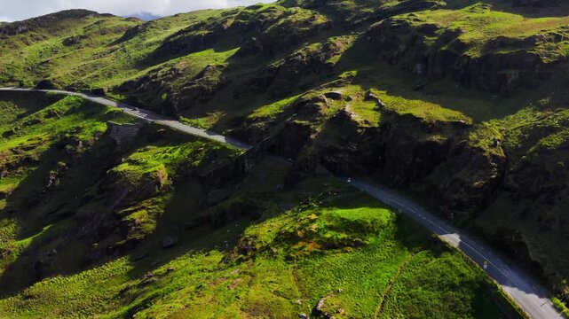 Aerial reverse orbit of cars driving through Turners Rock Tunnel in a sunlit mountain landscape