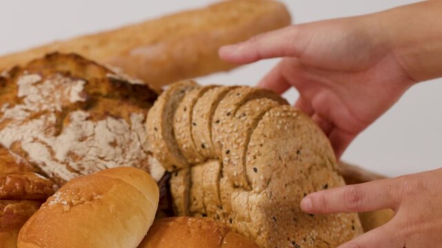 Hands Arranging Fresh Sliced Bread and Assorted Bakery Pastries