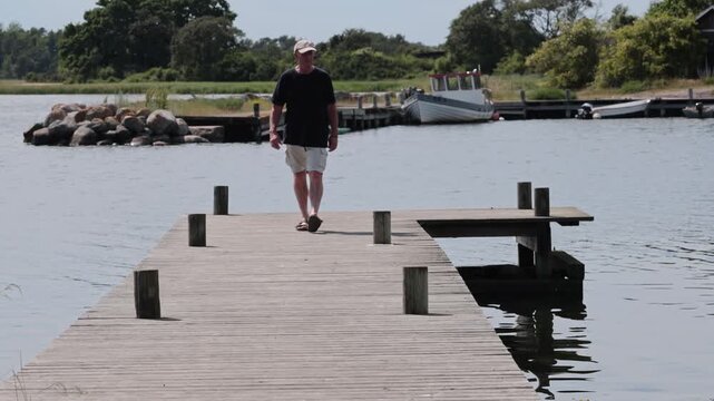 Lange Erik Lighthouse, Sweden A man walks on a pier in summer on the Baltic Sea on the northern tip of Oland island. 