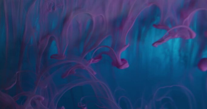 Water particles. Abstract ink. Defocused blue purple color acrylic smoke drip texture wet fluid moving on creative art background.