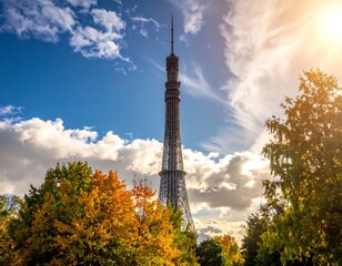 Obraz premium A towering structure piercing the sky. Colorful autumnal foliage frames the sturdy edifice under a partly cloudy sky illuminated by the sun
