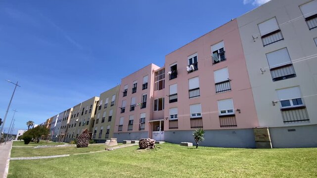 Row of colorful apartment buildings with balconies and shutters, showing coastal architecture and residential lifestyle in Alentejo