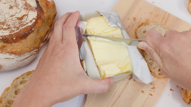 Hands Slicing Fresh Butter and Spreading it on Sourdough Bread