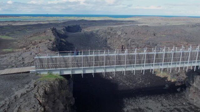 Aerial view of a man walking on the Bridge Between Continents, a footbridge over a major fissure in the Reykjanes peninsula, Iceland
