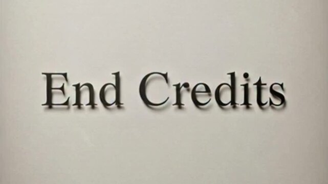 A close-up shot of the words 'End Credits' in a dark, elegant serif font with a subtle shadow effect, set against a plain light grey background.