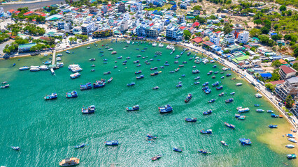 Fototapeta premium Breathtaking aerial view of Vinh Hy Bay, Vietnam, featuring emerald waters, colorful fishing boats, coastal villages, and rugged mountains. 