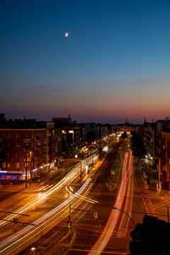Aerial view of Berlin at night with light trails from traffic on the streets, historic buildings, and a crescent moon in the twilight sky in Berlin, Berlin, Germany.