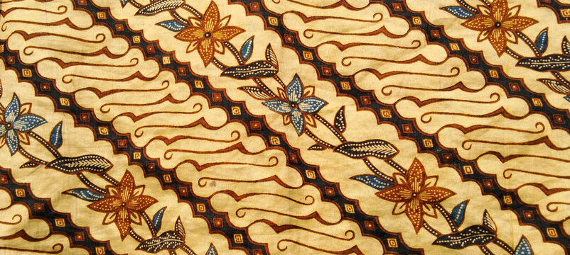 A close-up photo of traditional Indonesian batik cloth featuring a combination of classic parang motifs with floral and leaf ornaments.