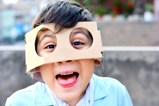 Latin kid wearing huge cardboard glasses and sticking the tongue out.