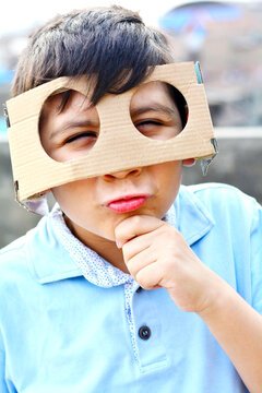 Funny portrait of thinking boy in cardboard glasses.