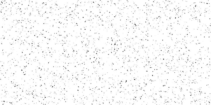 A close-up macro shot reveals a textured white surface speckled with numerous dark, random flecks, creating a subtle, abstract pattern.