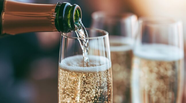 Pouring champagne from bottle into flute glass with bubbles
