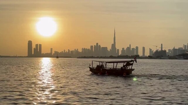 Traditional wooden dhow boat sailing on dubai creek at sunset with the city skyline in the background