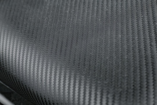 Curved carbon composite surface shows a precise woven pattern and subtle sheen, suitable for premium automotive, motorsport, engineering, and product visuals