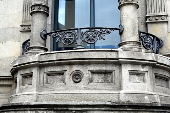 beautiful old cast iron balcony railing closeup detail. stucco finished facade. decorative columns. large glass window. classic architecture concept. travel and tourism in Europe