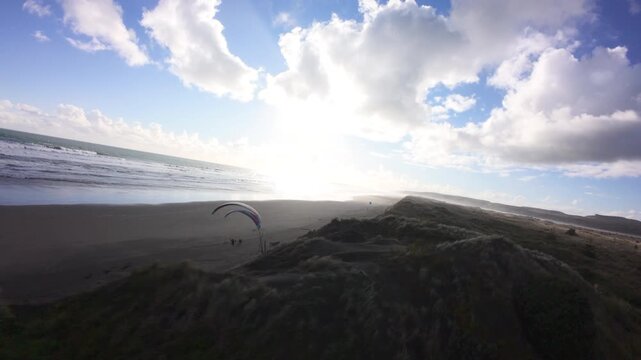 Two paragliders soaring above Port Waikato beach in New Zealand