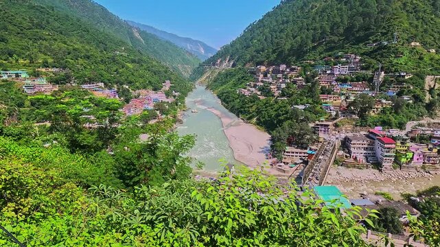 Panoramic mountain valley landscape of Karnaprayag town and river confluence from an elevated roadside vantage point.
