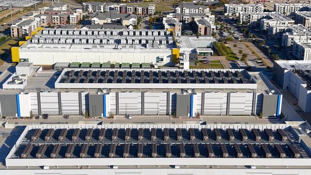 Aerial view of a large industrial AI data center complex in residential area.
