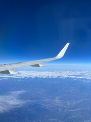 Obraz premium Airplane wing above clouds and blue sky during flight