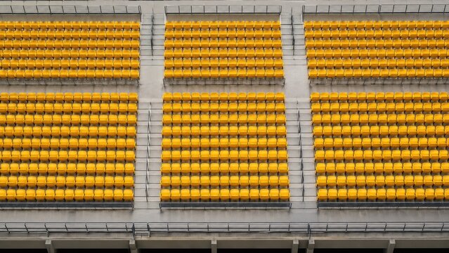 Rows of bright yellow stadium seats in tiered concrete stands, repeating pattern and symmetry in a modern sports arena seating section