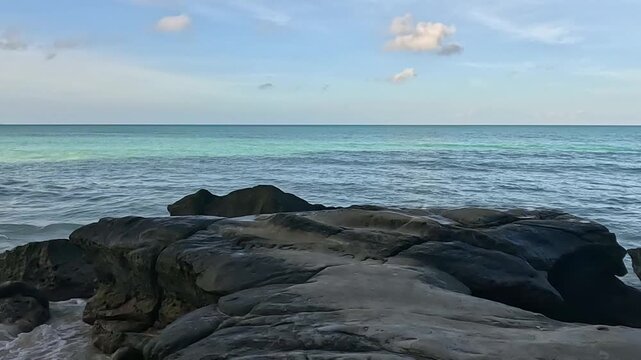 Rocky Coastline with Turquoise Ocean Waves under a Clear Blue Sky