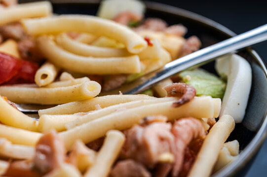 Delicious macaroni pasta salad with salmon, North Sea brown shrimps, and tomatoes in a dark bowl.