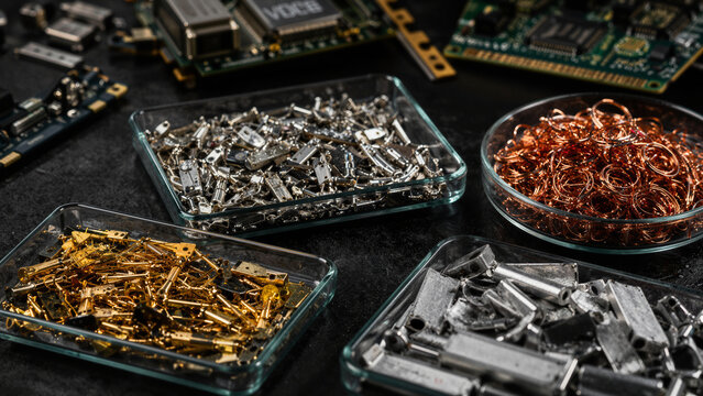 Metal parts and electronic components are arranged in bowls on a dark surface showing various materials and different sizes of items spread out around them