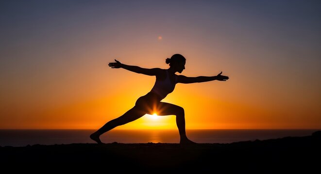 Silhouette of woman practicing yoga warrior pose on mountain top during sunset