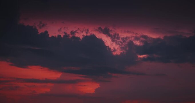 Dramatic red sunset sky featuring heavy dark rain clouds and climate change concept.