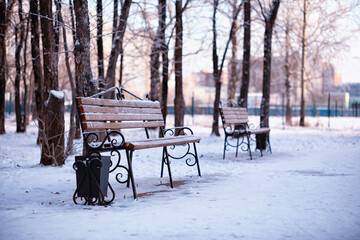 Fototapeta premium park bench on a winter alley at snowfall. bench with snow after snowstorm or in snow calamity in europe