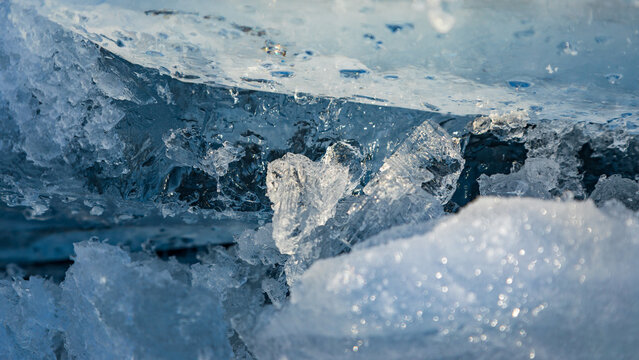 View of crystalline ice formations on the frozen surface of Lake Baikal with sunlight reflecting on the clear blue ice in Davsha, Buryatia, Russia.