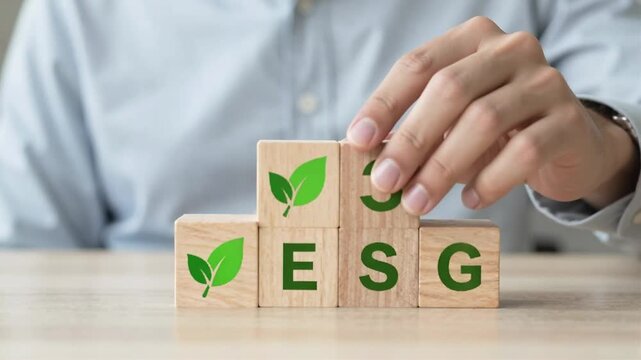 Businessperson arranging wooden blocks with ESG and green checkmarks on table.