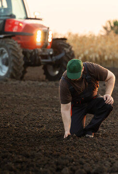 Young farmer on farmland with tractor in background