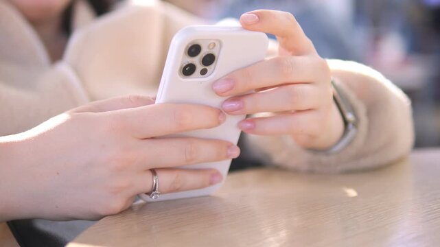 Hands scroll phone at table, sunlit. Fingers tap screen, calm focus. Perfect for digital life, cafe, work, leisure scenes
