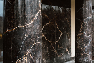 Naklejka premium Architectural detail of modern building entrance with blackmarble columns Elegant marble column detail inside luxury building entrance symbolizing wealth, status, and refined interior design