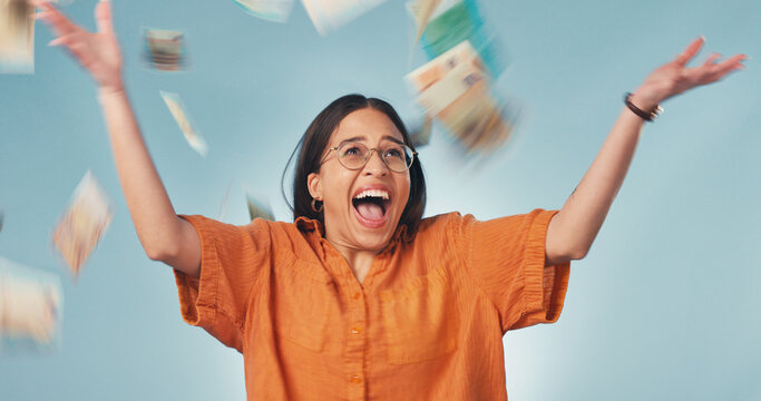 Excited, celebrate and woman in studio with money rain, lottery success and giveaway prize. Happy, winner and person with cash for winning competition, promotion and income bonus on blue background