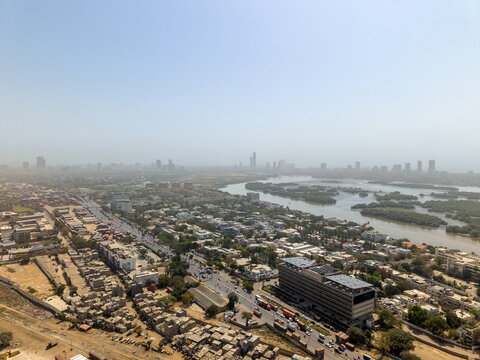 Aerial view of the sprawling Karachi skyline featuring dense urban development, a winding creek, and busy roads in Karachi, Sindh, Pakistan.