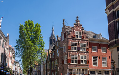 Fototapeta premium Historic buildings in Delft, Netherlands, Delft City Hall and the Gothic tower of Nieuwe Kerk, blue sky.