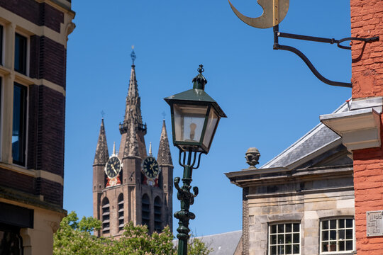 Vintage street lamp framing leaning Oude Kerk tower in historic Delft city center, Netherlands