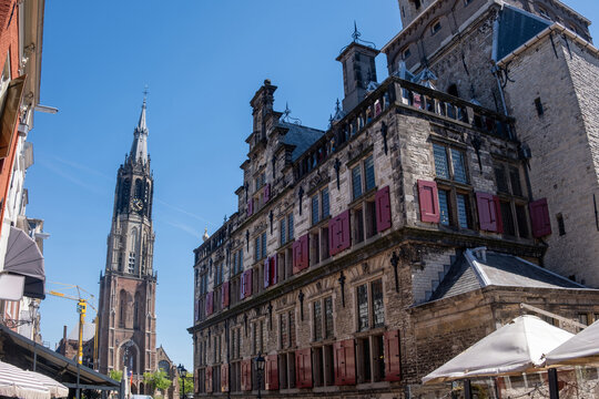 Nieuwe Kerk tower and historic stone facades in Delft city center under clear blue sky, Netherlands