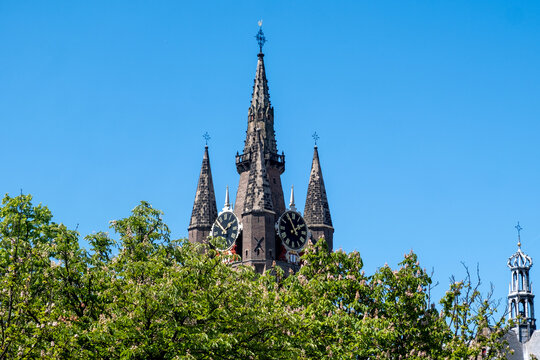 Oude Kerk tower rising above narrow streets and traditional brick buildings in Delft city center, Netherlands.