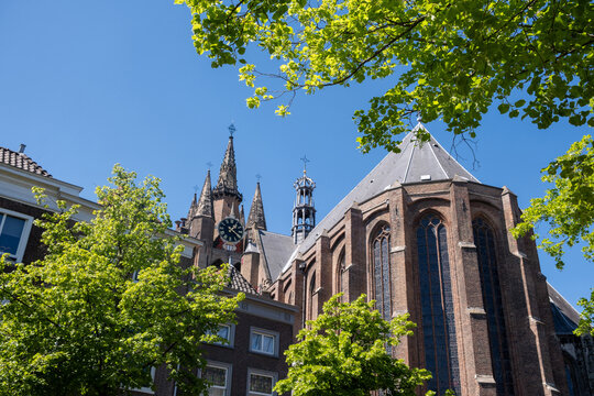 Oude Kerk tower rising above narrow streets and traditional brick buildings in Delft city center, Netherlands.