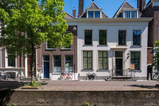 Historic canal houses beneath leafy trees in Delft city centre spring sunlight Netherlands