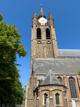 Oude Kerk tower and historic brick church architecture under blue sky in Delft city center, Netherlands.