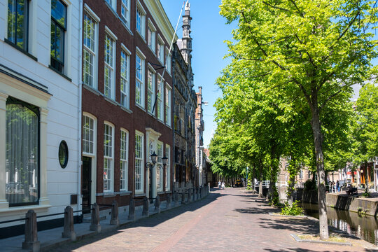 Historic canal houses and arched bridge in Delft City Centre on sunny spring day, Netherlands