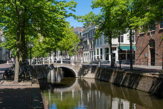Historic canal houses and arched bridge in Delft City Centre on sunny spring day, Netherlands